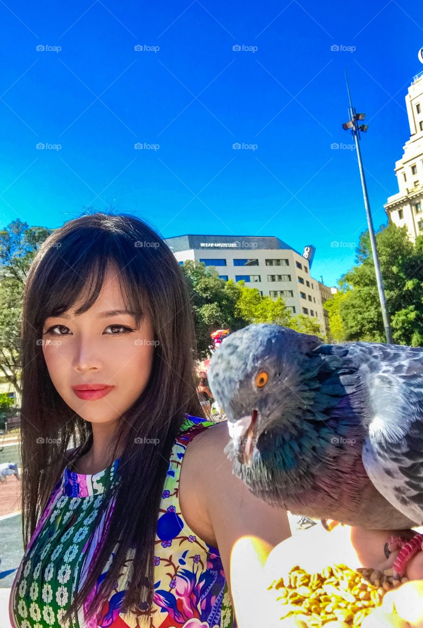 Pretty asian girl feeding pigeons 