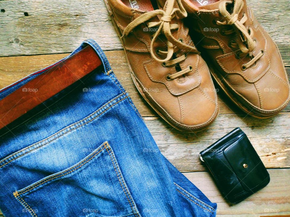 men's leather shoes, blue jeans with a belt and a black purse