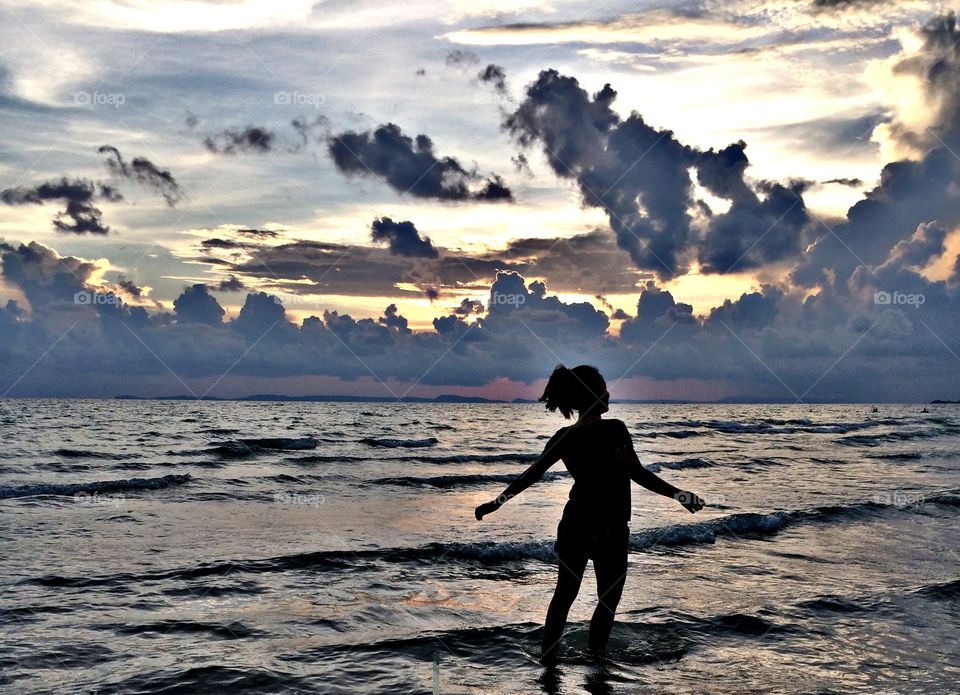 Sunset on the beach with bare feet in the sea.