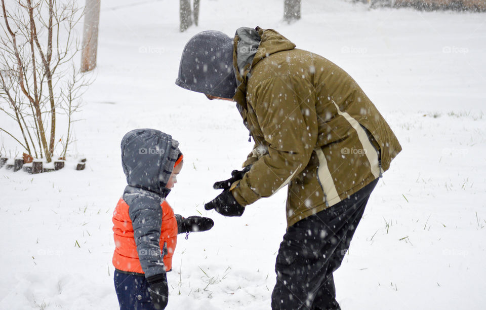 Father and son playing in the snow together outdoors in the winter