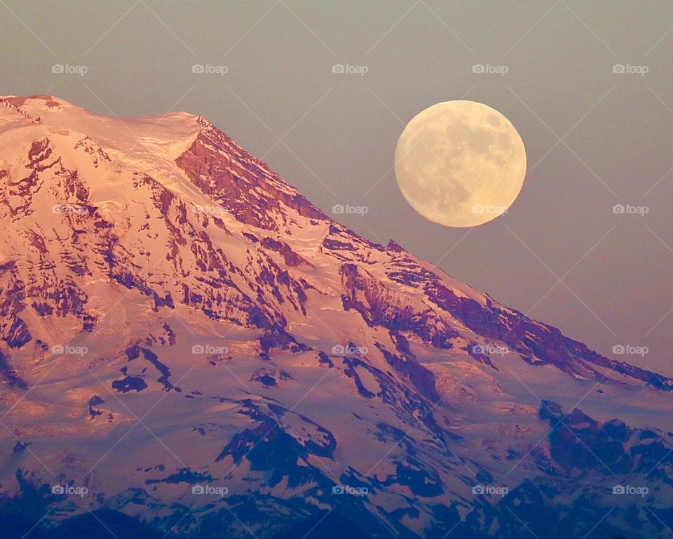 A super moon rises from behind Mount Rainier on a warm summer night in Washington State 