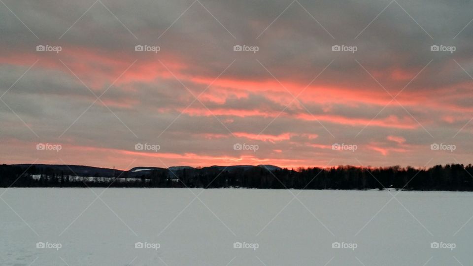 Sunset with pink clouds over a snowy lake