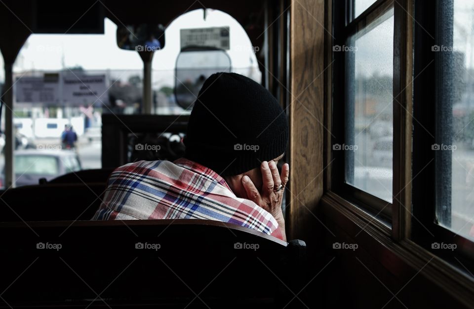 old lady sitting in a bus looking out of the window. thinking