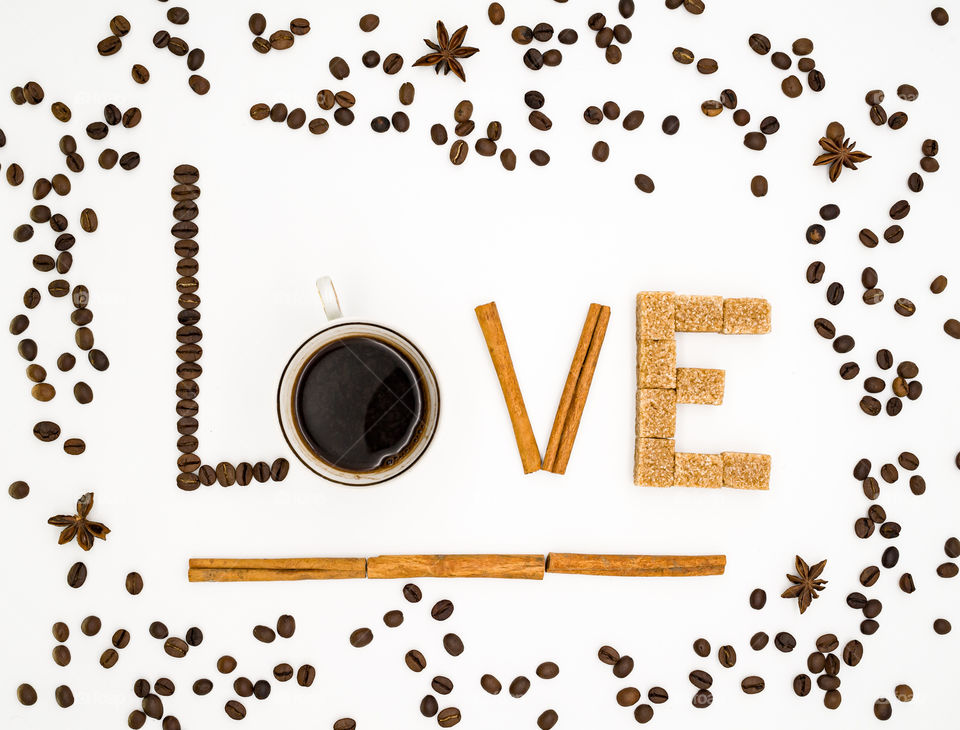 The inscription "love" collected from coffee beans, cinnamon sticks, star anise and cane sugar. On white background.