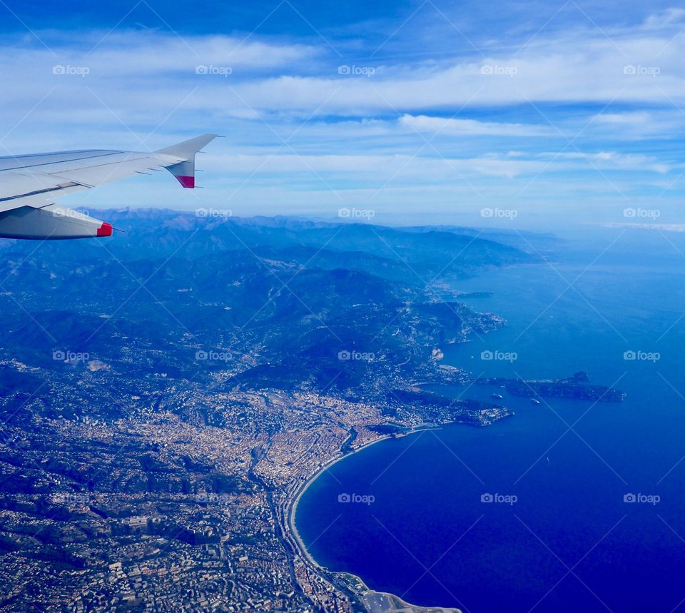 View of the French Riviera from behind wing on airplane flying over Nice, France.