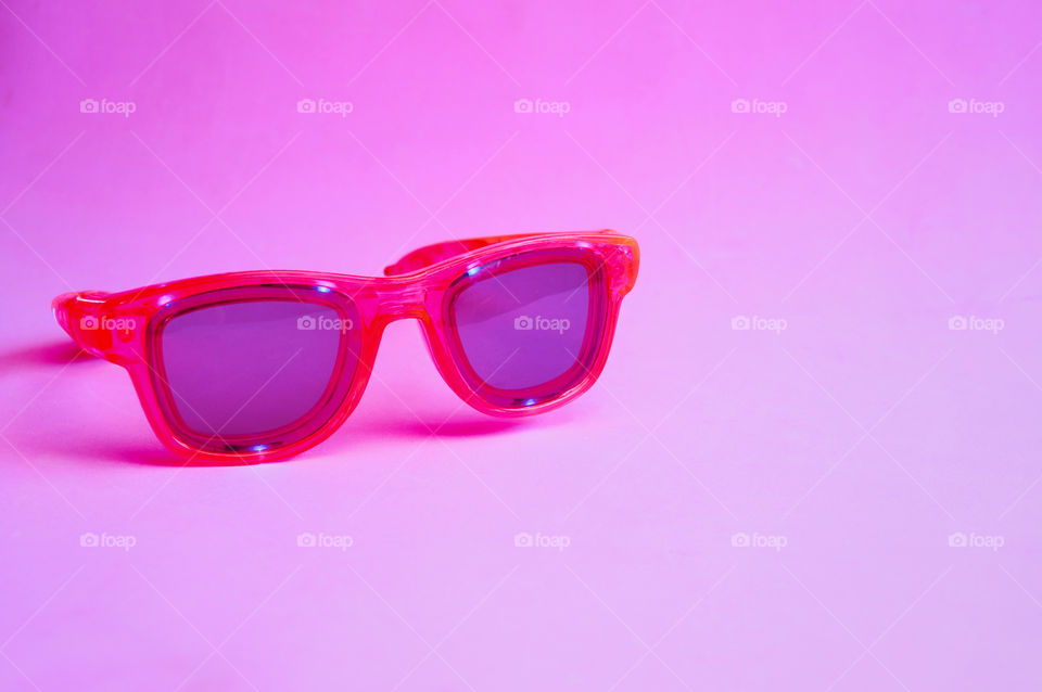 Pink glasses on purple background with copy space 
