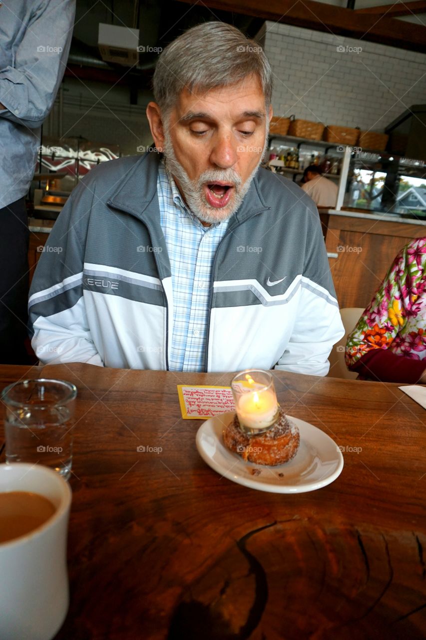 Portrait of a man blowing candle in restaurant