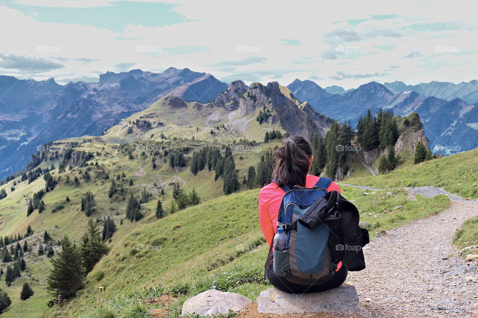 Hiker sitting on rock admiring view.