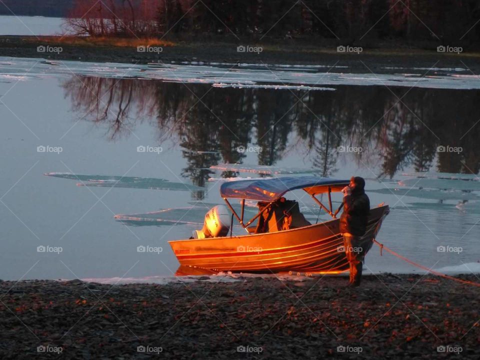 A man and his boat at sunset.