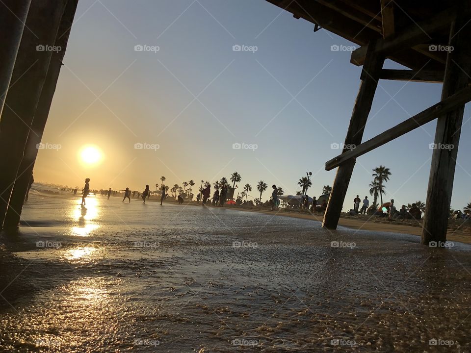 Capture of a bright sunset from under the Balboa Pier in Newport Beach, CA with people in the background