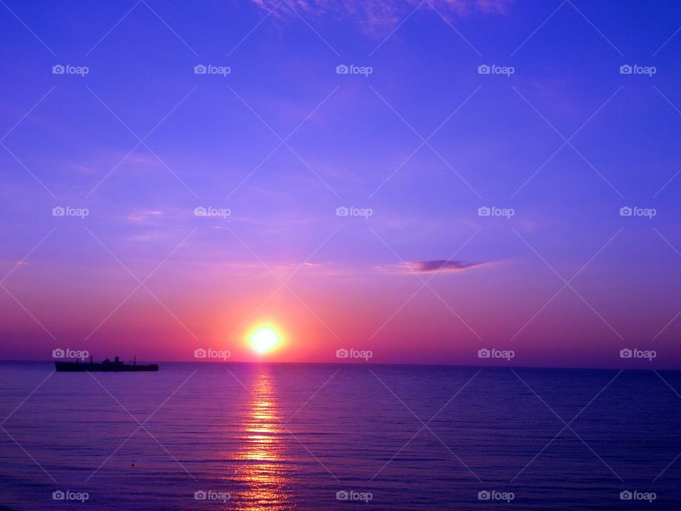 Sunset over sea with silhouetted boat