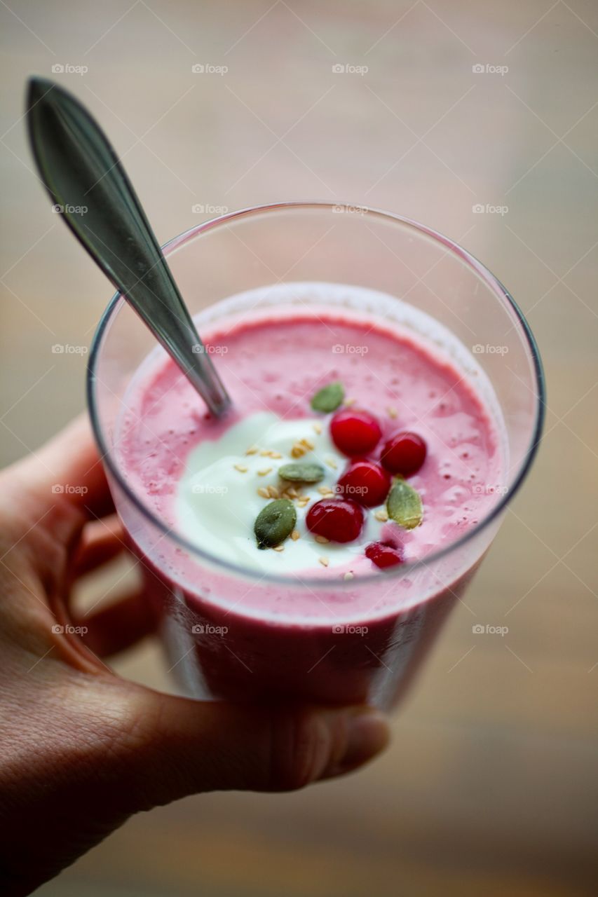 A person holding smoothie in glass