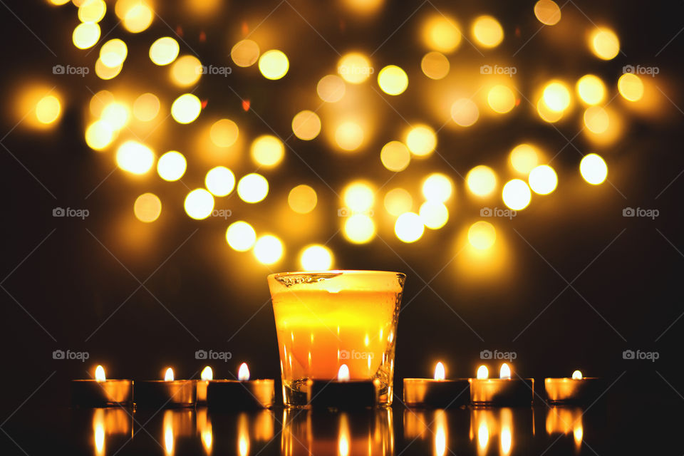 Burning candles with festive bokeh on a black background. Holiday concept. the concept of prayer and hope.