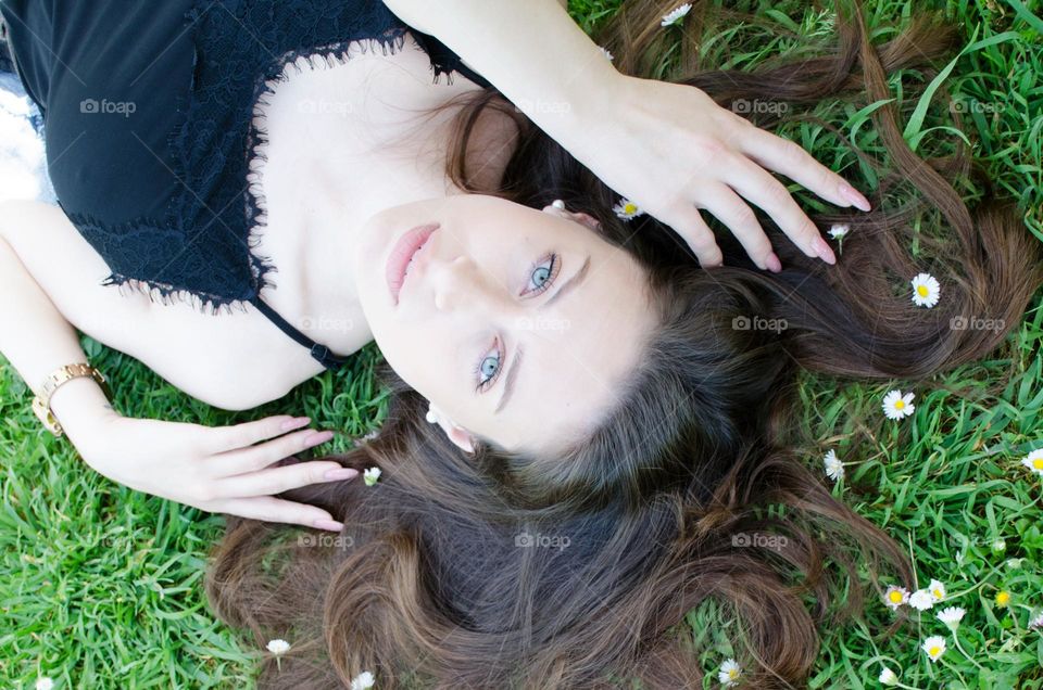 Portrait of Beautiful Young Girl on Background of Daisies