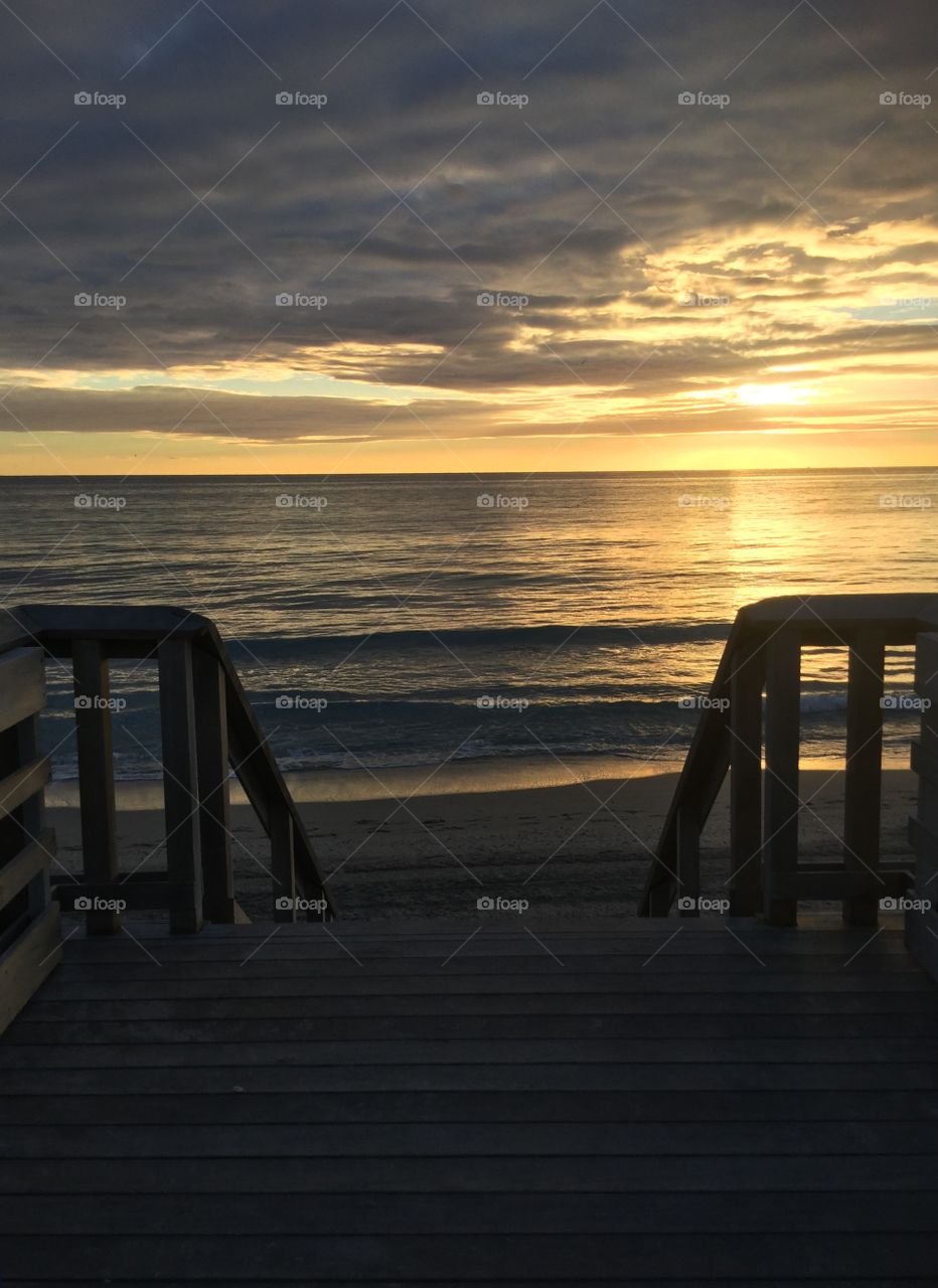 Walking onto beach from wood stairs to watch sunrise 