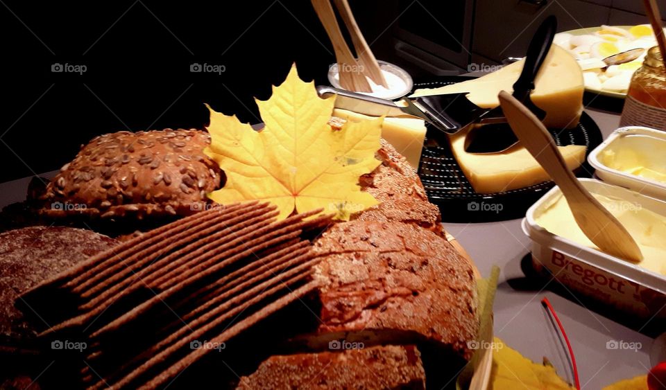 Table with bread, butter, cheese, autumn leaf