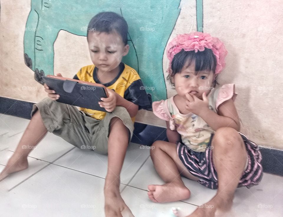 A boy playing a gain on a tab and friend