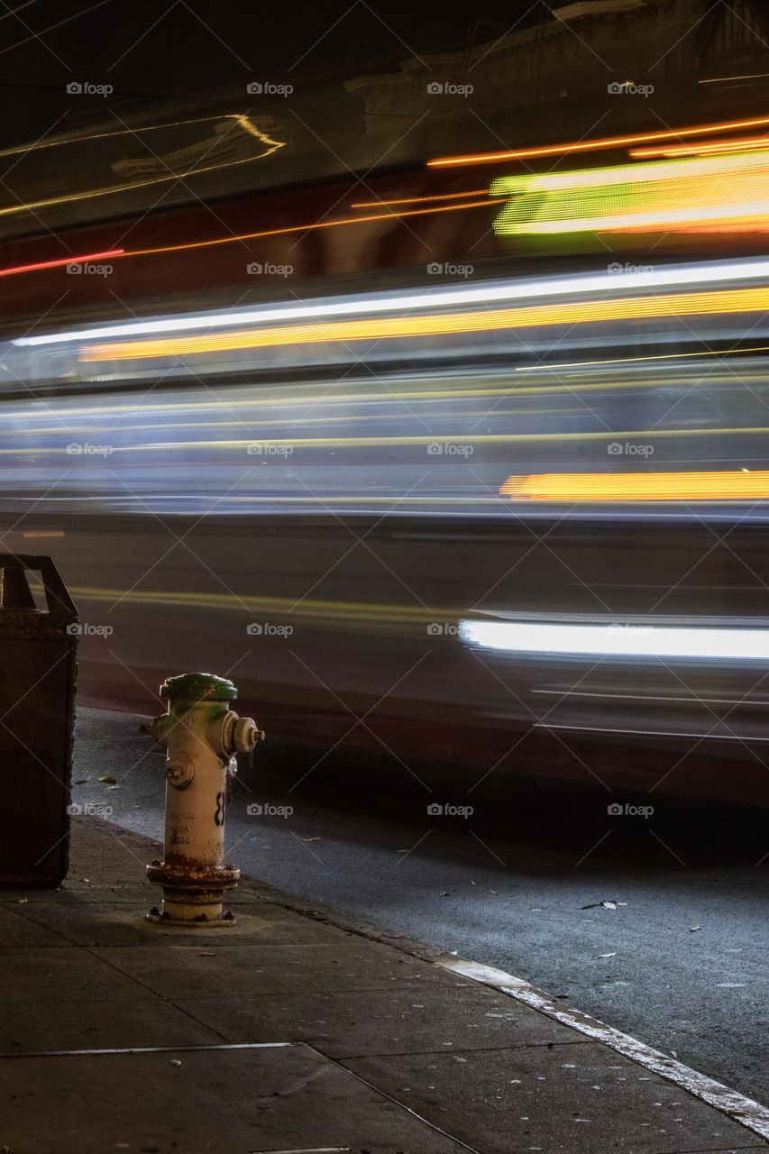 Long exposure of the 22 Fillmore bus at night in San Francisco on Fillmore Street and Bay Street at the bus stop as it moves down the street 