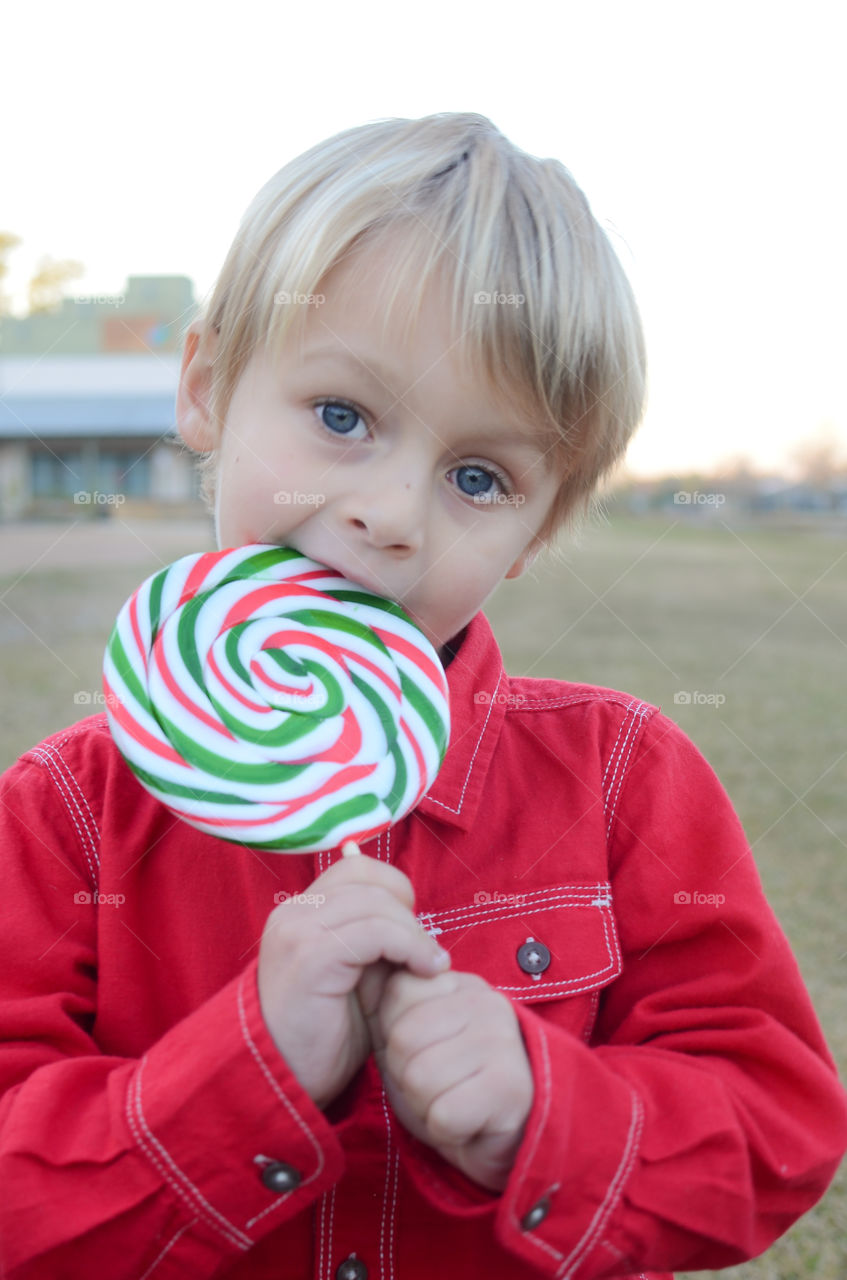 Little boy eating swirl lollipop