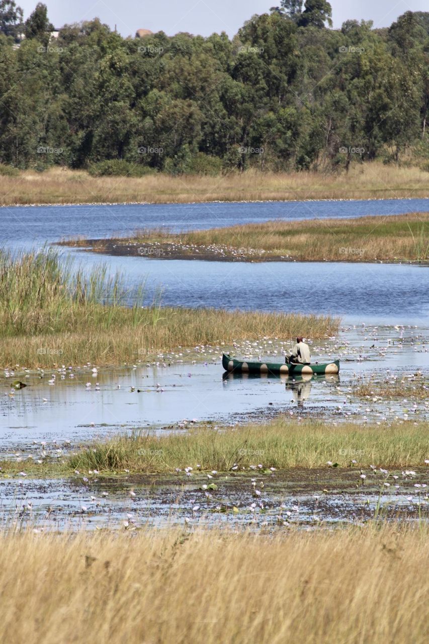 A scenic view of a fisherman in a canoe at Cleveland Dam in Zimbabwe 