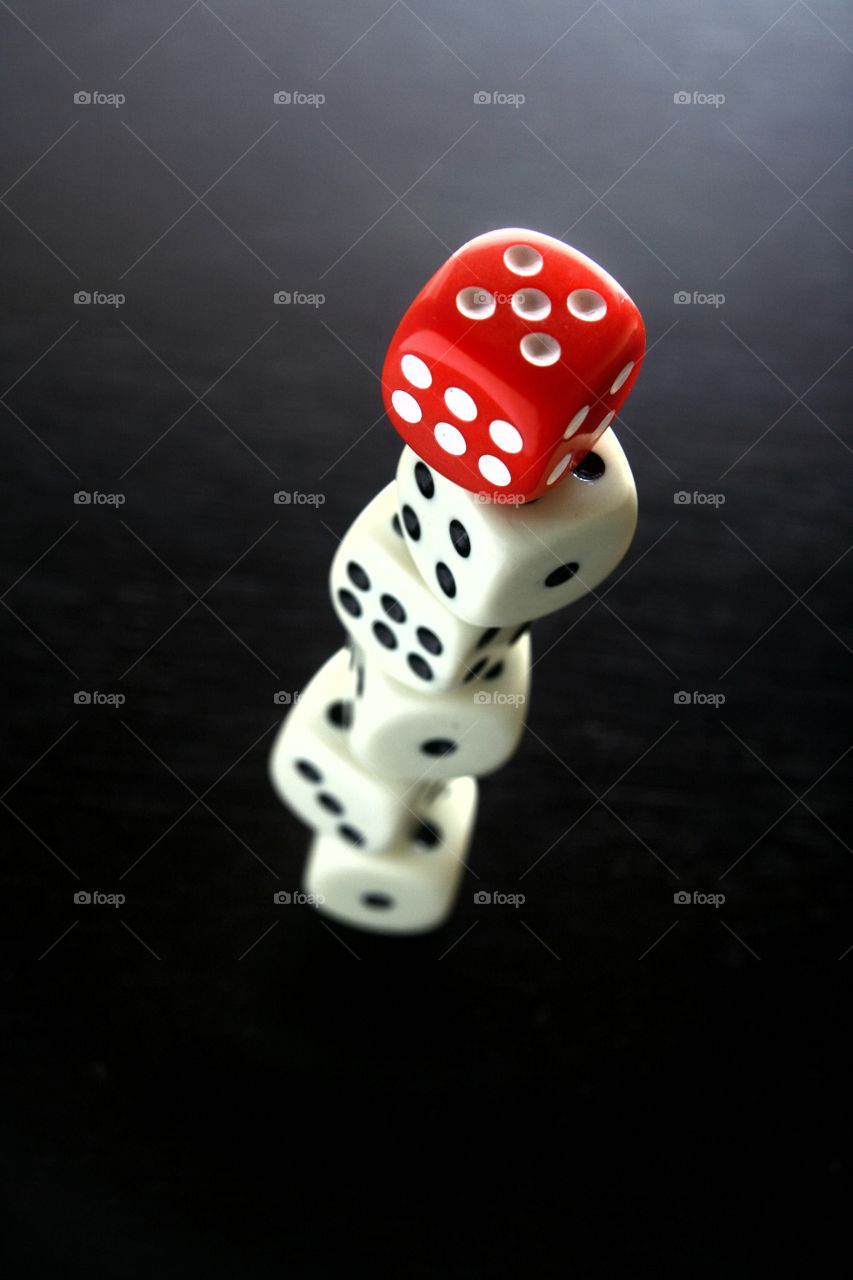 red and white game dice. 1 red game dice on top of  stacked 5 white game dice