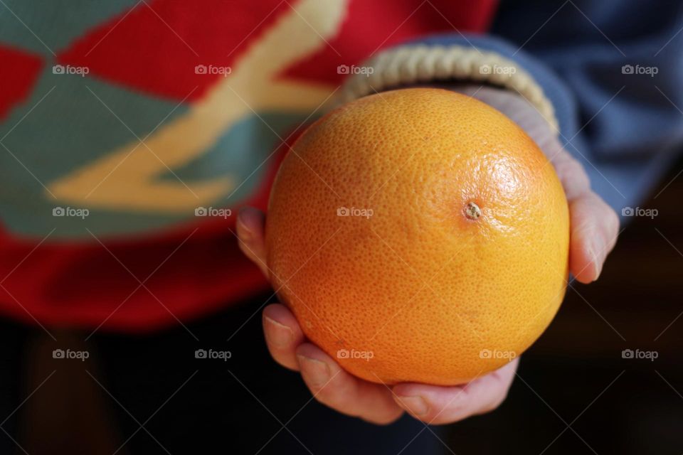 Close-up of a yellow grapefruit being held by a woman