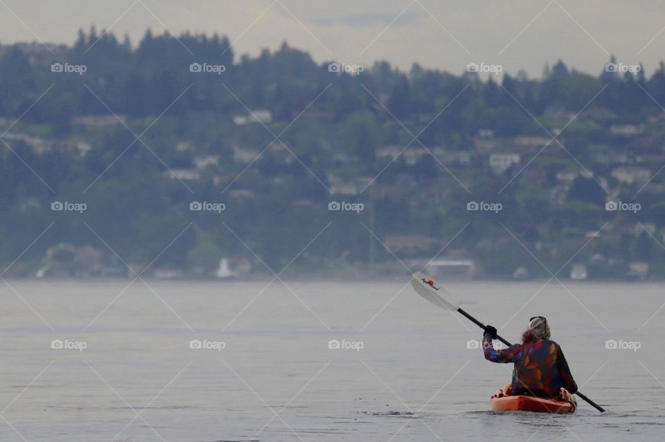 A mature female kayaks the calm waters of Dalco Passage near Point Defiance in Tacoma, Washington 