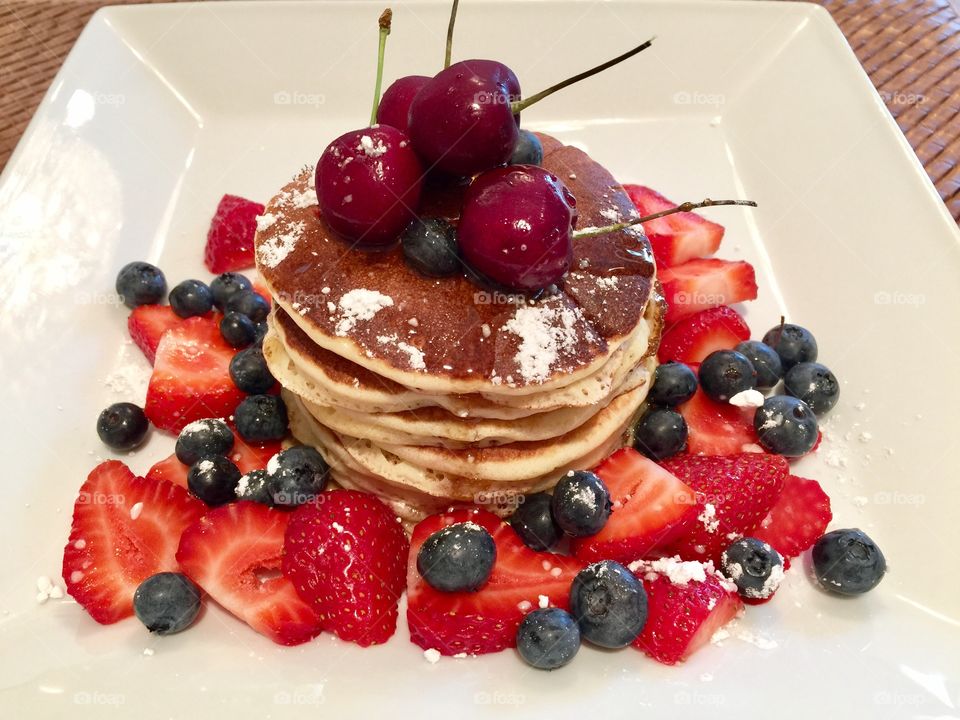 Multigrain Flaxseed Coconut Pancakes with blueberries, strawberries organic maple syrup, hint of confectioners & cherries on top