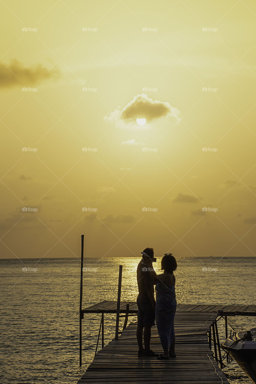 Tourists take photos on a wooden bridge in the sea and Golden reflections of the Sun