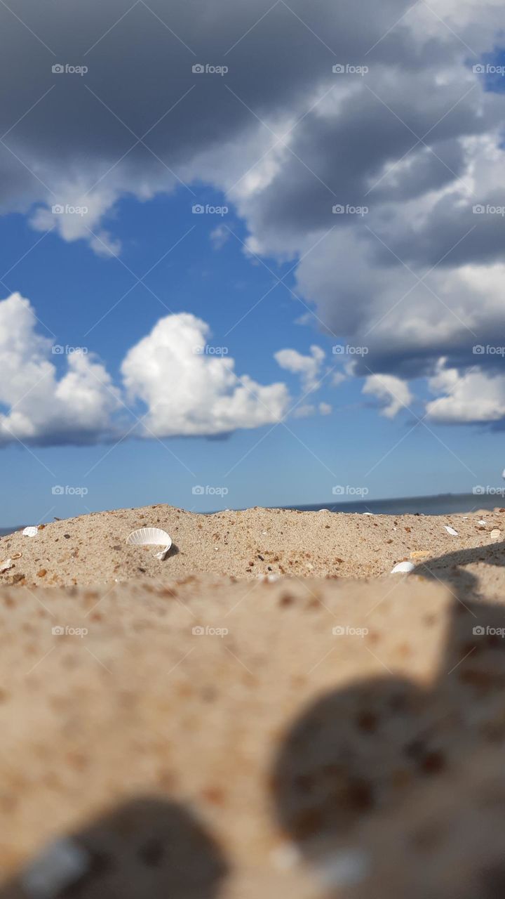 sand beach on Baltic sea shore with white shell salt water blue sky and white clouds on sunny day