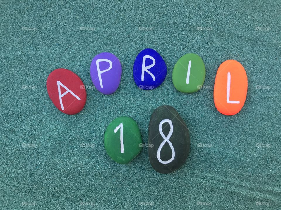 18 April, calendar date with colored stones over green sand