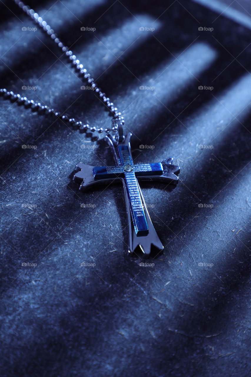 Cross pendant on dark background with shadows
