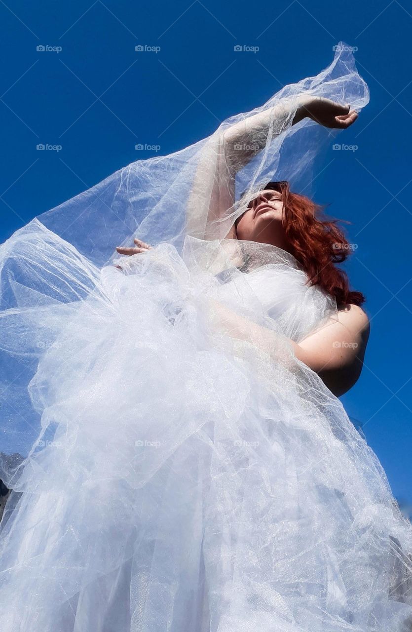 Original photo of a girl in a chiffon skirt against a blue sky background