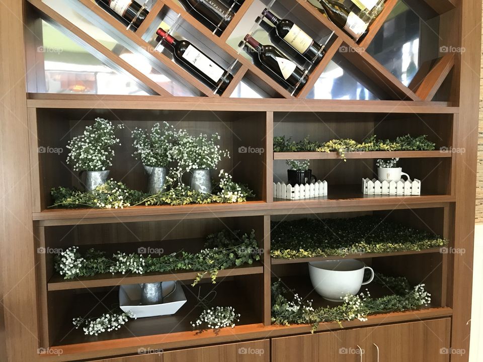 Plants inside a cute cafe and wine bar with a wine rack above it and shelves full of greenery
