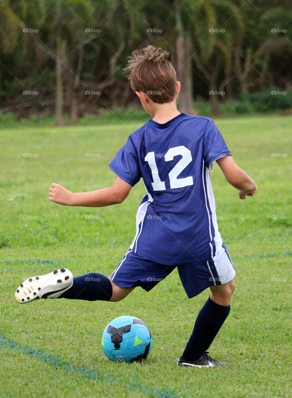 Back of boy kicking ball during soccer game