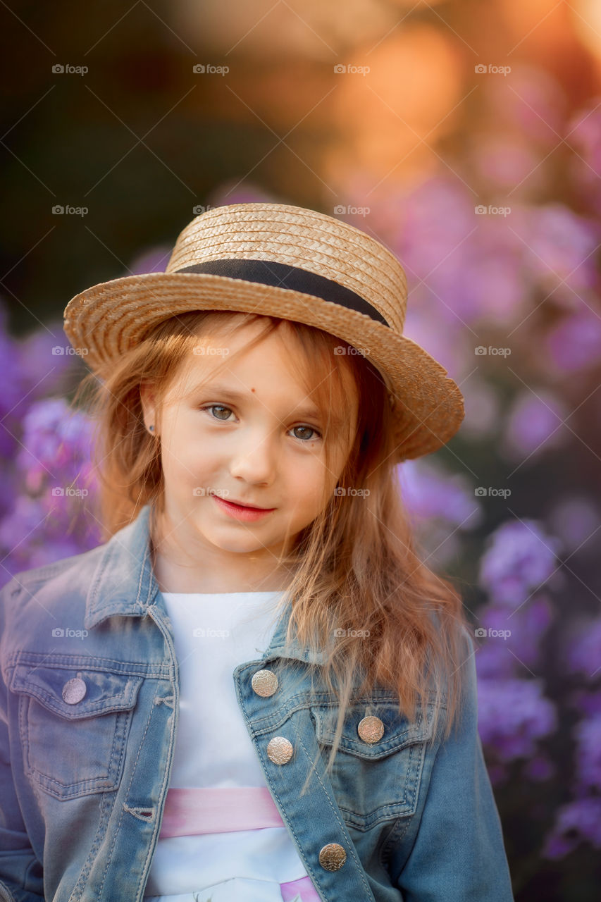 Cute little girl portrait in blossom meadow at sunset 