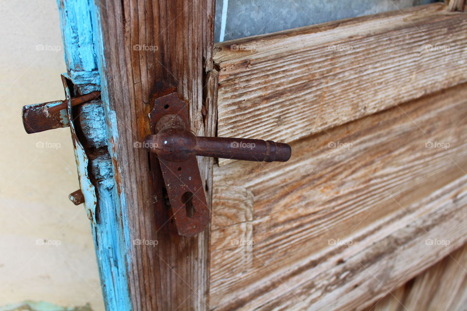 Broken wooden blue door with rusted handle outdoors