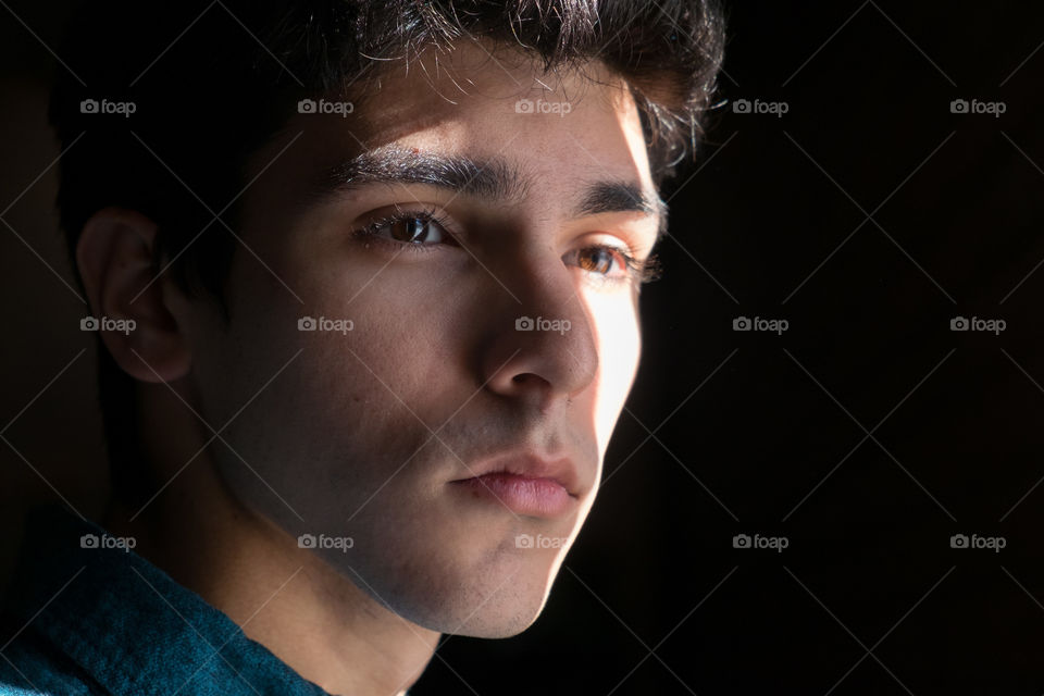 Young man's face cast in a strong shadow