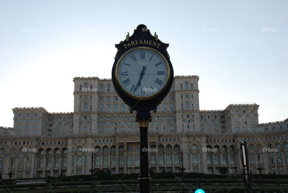 Gilded clock in front of the second largest building in the world