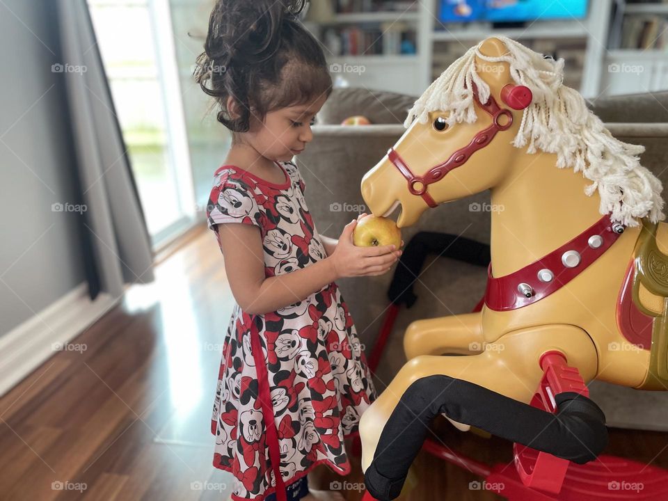 Toddler girl feeds play horse an apple, feeding apples to horses, playing with horses, little girl loves horses, radio flyer horse, pretend play