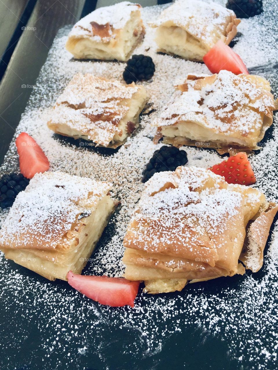 Bougatsa Greek filo custard pie decorated with powder sugar and strawberries 