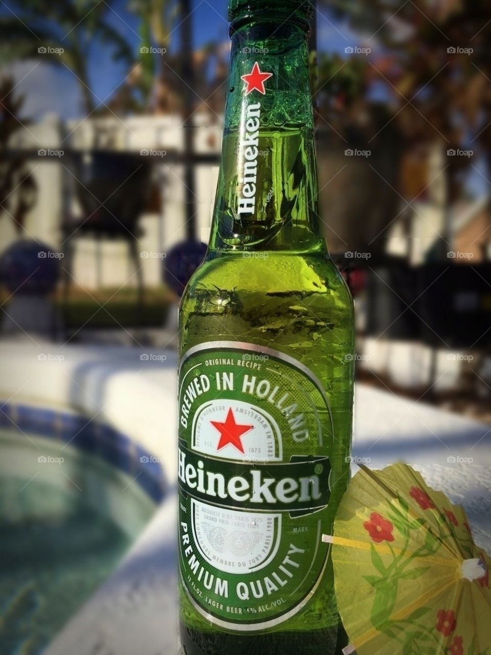 Heineken bottled beer with yellow mini umbrella by the pool