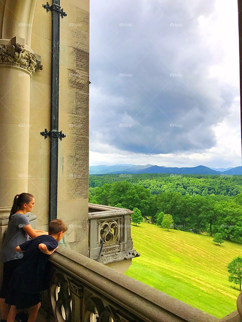 Children overlooking the mountains from the loggia of a castle