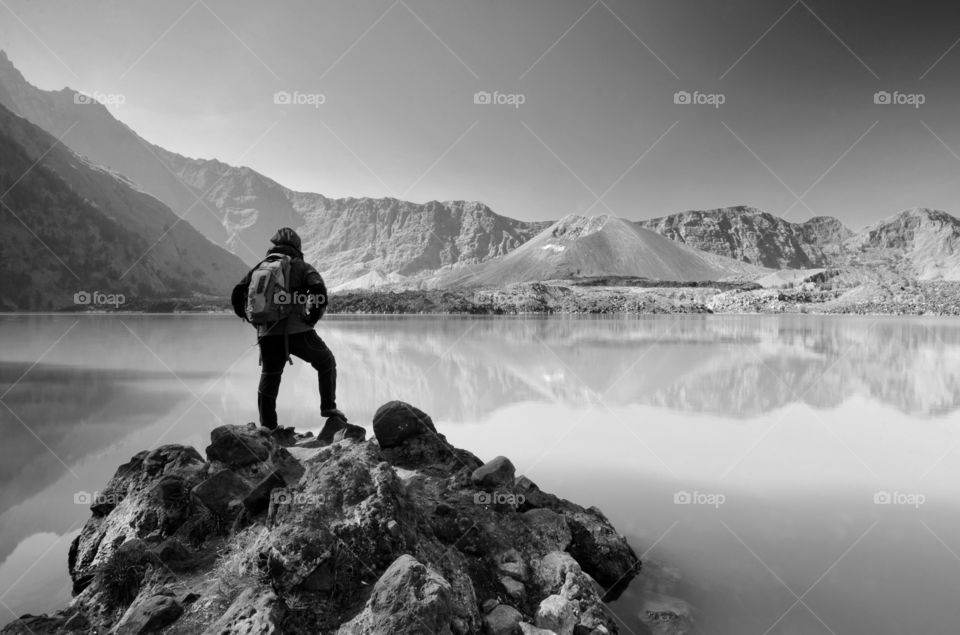 black and white Beautiful nature background with unidentified hiker at Segara Anak Lake. Mount Rinjani is an active volcano in Lombok, indonesia. Soft focus due to long exposure.