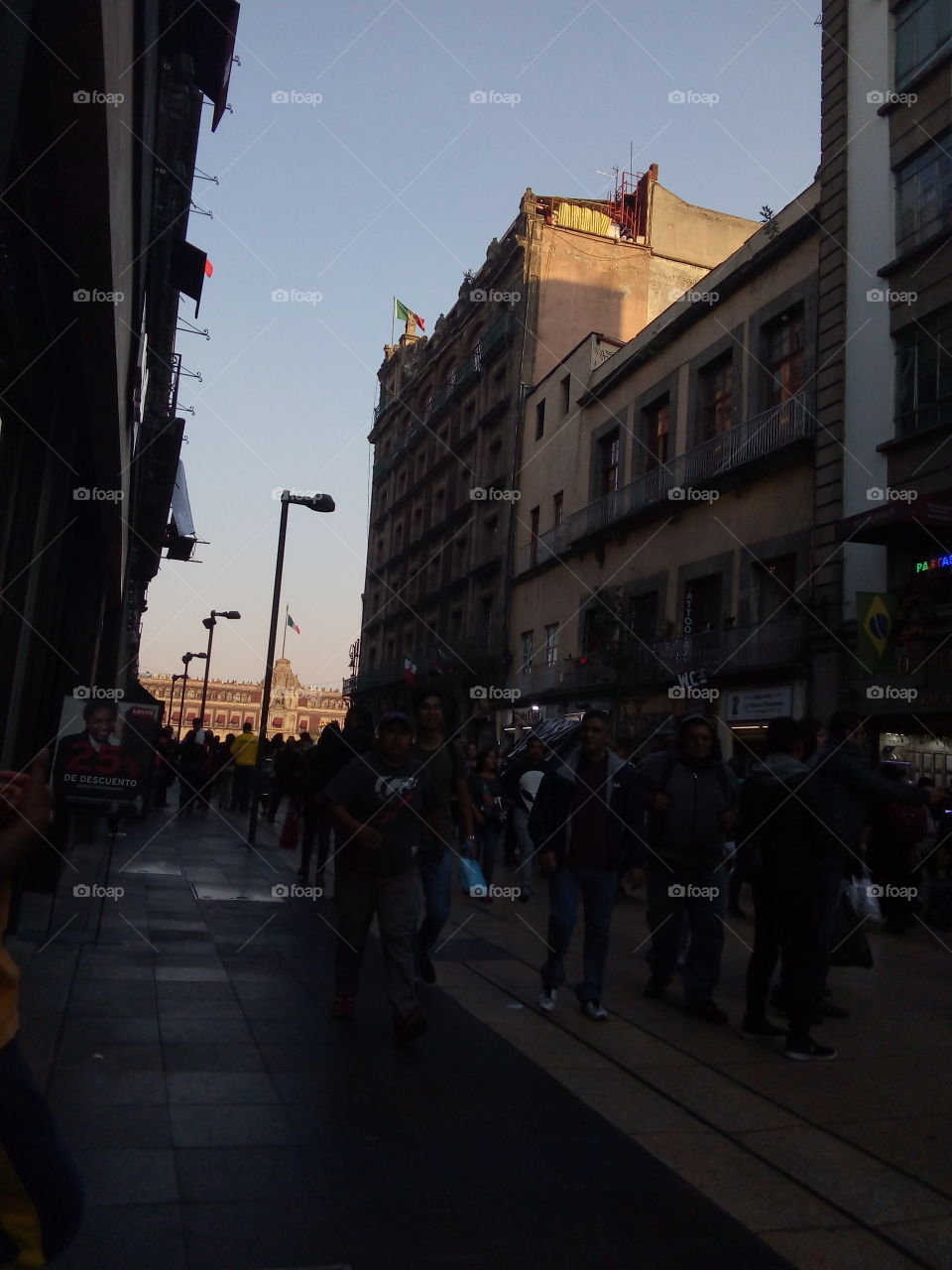 gente caminando por la calle, juego de luz y sombra en los edificios. De fondo el Palacio Nacional de la Ciudad de México