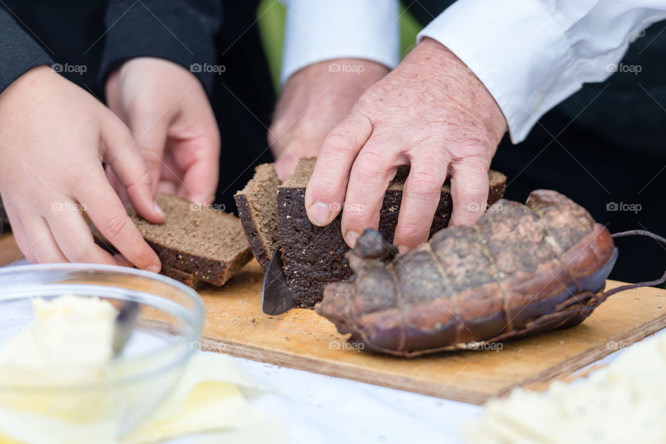 man hands cuting rye bread on the wooden board, selective focus