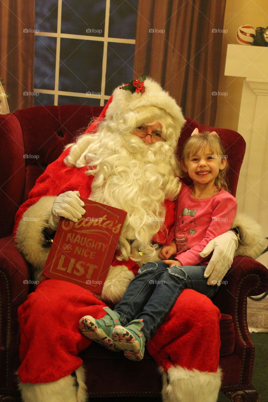 Cute little girl sitting on Santa's lap