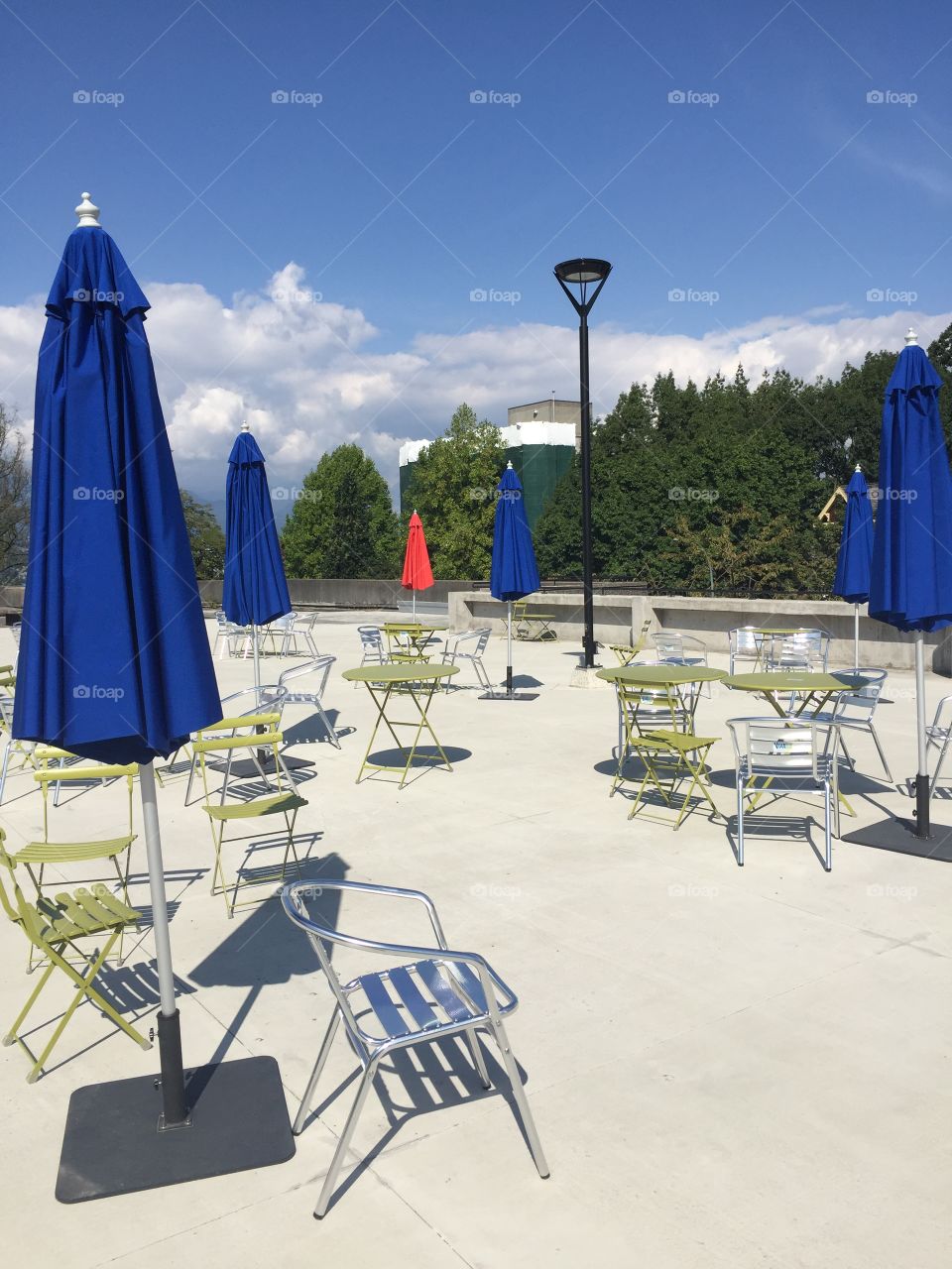 An empty patio at city hall on a sunny Saturday with a solo red umbrella amongst the blue in Vancouver, British Columbia.