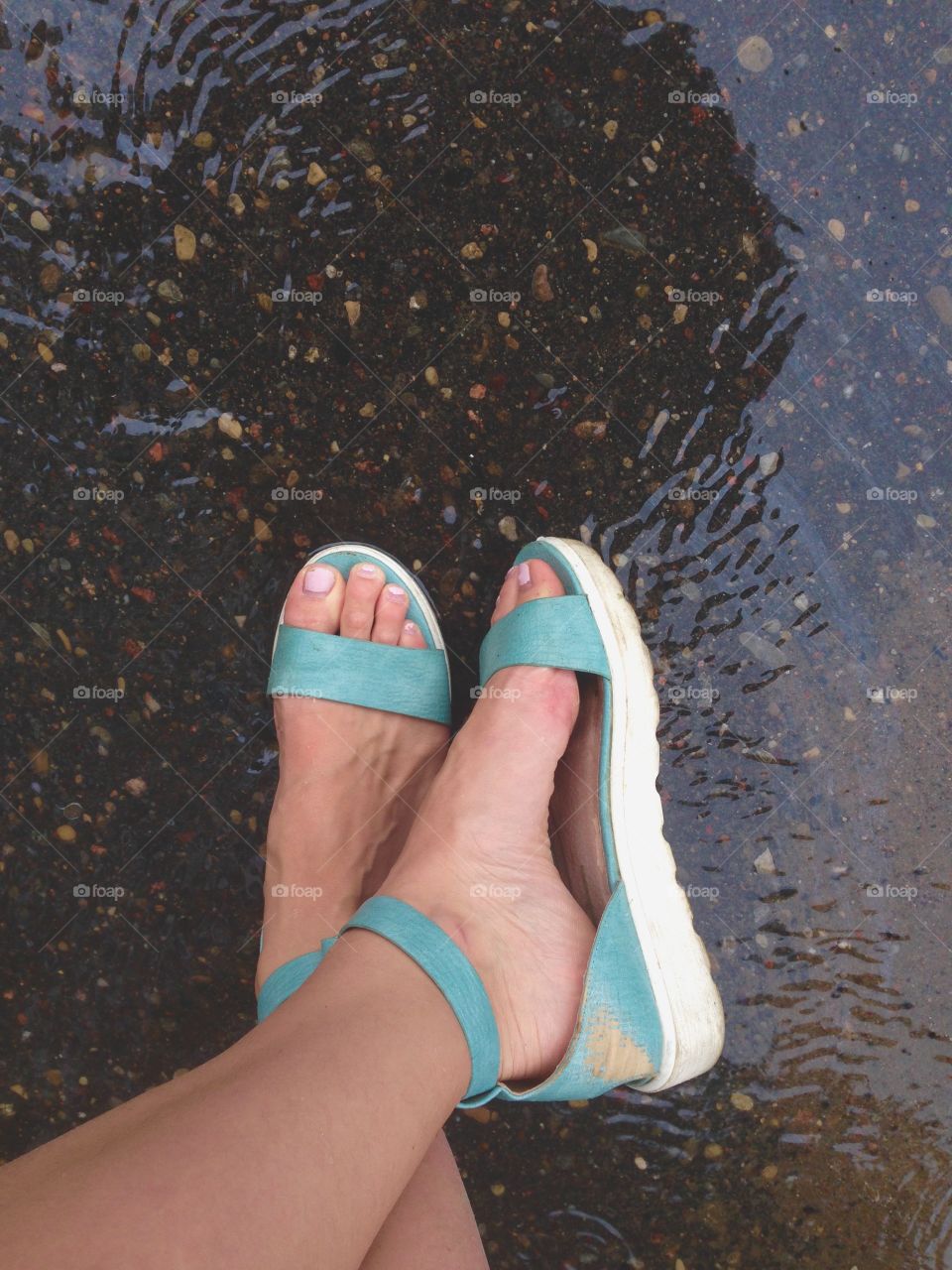 Green comfortable sandals in front of puddle 