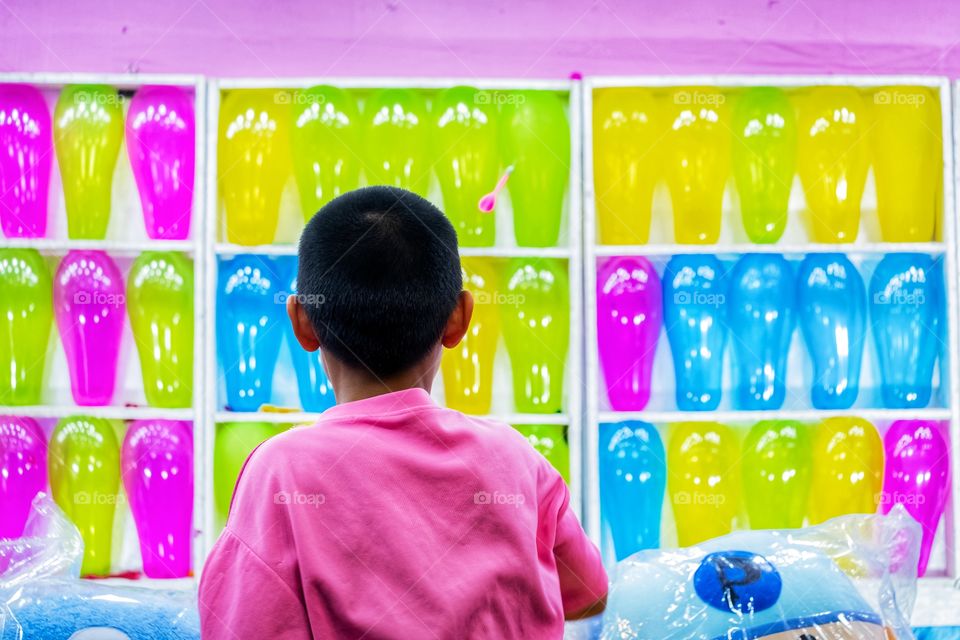 A boy is playing darts at Thai temple fair festivals